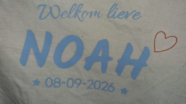 Detail van naam en geboortedatum Bedrukking van gepersonaliseerde babyromper met naam